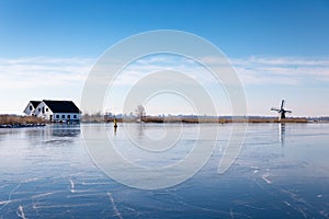 Ice on the Dieperpoel Kagerplassen in front of a windmill and house on the Kogjespolder