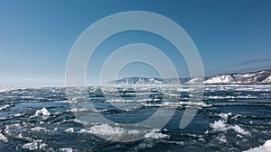 Ice drift on the river. Blue ice floes and melted snow on the surface of the water.