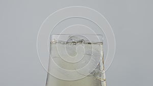 Ice falling white wine glass close up. Cold drink splashing in elegant goblet.