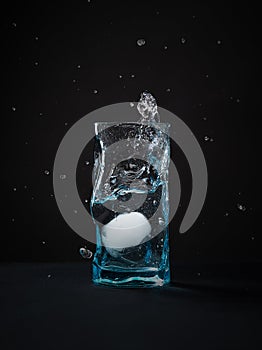 Ice falls into the glass. splash of frozen water. Blue beautiful wine glass