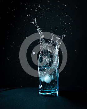 Ice falls into the glass. splash of frozen water in the form of a crown. Blue beautiful wine glass