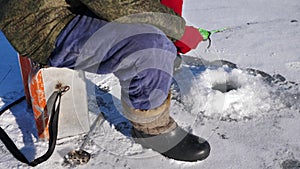 Ice fishing on a frozen lake. A man is fishing in an ice hole