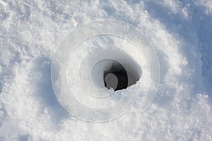 Ice fishing hole on the surface of the river in winter