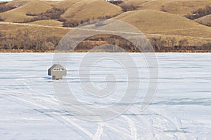 Ice fishing hut in middle of frozen lake