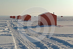 Ice fishing huts on a frozen lake in Ontario at sunset