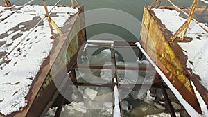 Ice floating on river in spring time under old pier.