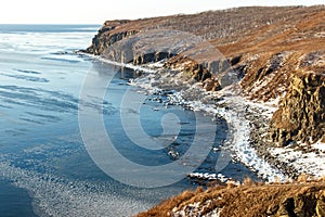 Ice floes floating in the winter sea off the snow-covered coast of Cape Tobizin on the Russian island