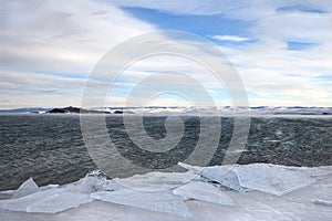 Ice floes at frozen coast of stormy lake in winter