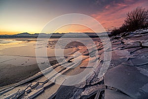 Ice floes on the lake shore. Colorful sky during sunrise on cold winter morning.Dam Liptovska Mara, Slovakia