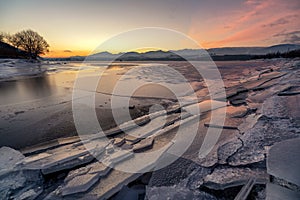 Ice floes on the lake shore. Colorful sky during sunrise on cold winter morning.Dam Liptovska Mara, Slovakia