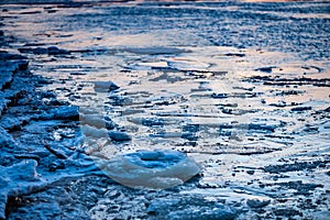 Ice fragments covered with snow on frozen river water.