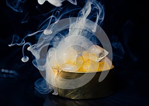 Ice in a golden box with smoke, colorful smoke, blue smoke, gray smoke, ice in syrup, delicious ice. space picture on dark backgro