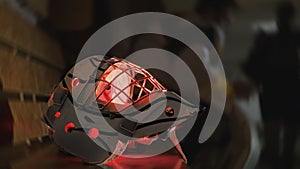 Ice hockey goalkeeper goaltender mask helmet with red glow light. Protective equipment gear is on bench in locker room