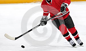 Ice hockey player dribbling puck on rink