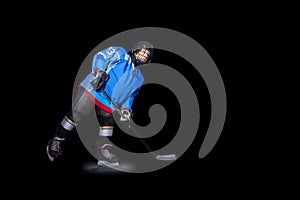 Ice hockey player with stick over black background