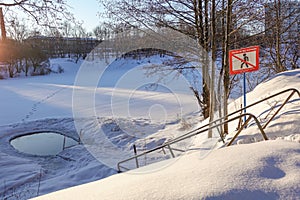 Ice hole in the lake in winter is equipped with a ladder for launching. prohibition sign with the inscription: do not go on the