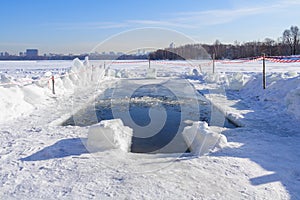 Ice-hole on the river illuminated by sunlight