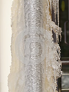 Ice and icicles on a drainpipe. Drainpipe covered with ice and icicles