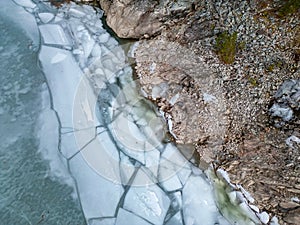 Ice at the lake by rocky shore. Aerial View. British Columbia landscape. Canada