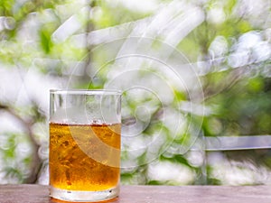 Ice lemon tea on wood table with nature green blur bokeh background