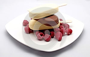 Ice lollies and rasperries on a white plate