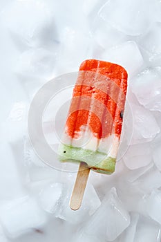 Ice lolly with vanilla smoothie on ice cubes. Homemade cold healthy dessert. Top view