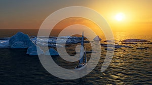 Ice melting, climate change. Sailboat sailing in the Antarctic Ocean. Arctic sea, drifting iceberg