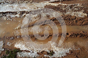 Ice on mud red clay soil road with tyres lines