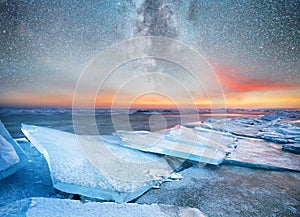 Ice on the ocean shore at the night time. Sea bay and stars at the night time. Milky way above ocean, Norway.