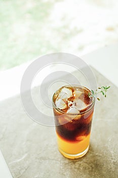 The ice of orange juice and black coffee on grey marble, Summer drinks for Asian people. Vertical photo