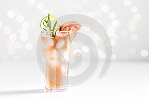 Ice paloma cocktail of tequila, lime juice, grapefruit and soda, decorated with rosemary stands in a glass on a background