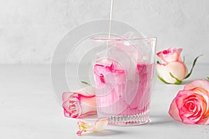 Ice rose latte in glass with pink flowers and petal on white or grey background