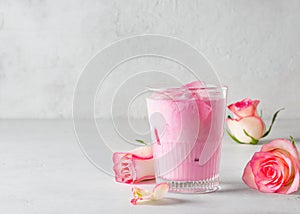 Ice rose latte in glass with pink flowers and petal on white or grey background