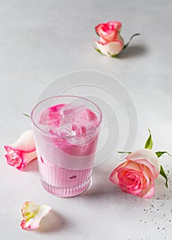 Ice rose latte in glass with pink flowers and petal on white or grey background