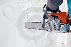 Ice sculpture carving man use chainsaw cut frozen winter