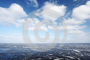 Ice on sea water and white clouds