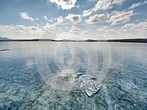 Ice shards on a frozen lake. The rays of the sun creat rainbow shadows