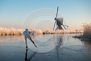 Ice skating past frosted reeds and a windmill