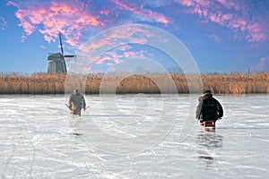 Ice sledging on a cold winterday at the windmill in the Netherlands at sunset