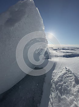 Ice slopes in sunny winter day, transparent ice of blue color, purely blue sky, long shadows, a pure snow-covered virgin