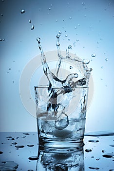 Ice splashing in a cool glass of water