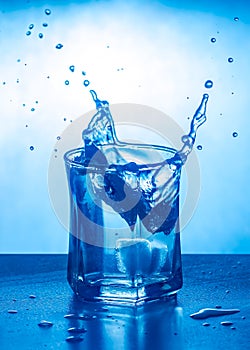 Ice splashing in a cool glass of water