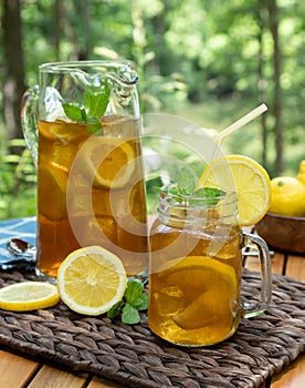 Ice tea in glass jar and pitcher with lemon and mint