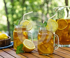 Ice tea in glass and pitcher with lemon and mint