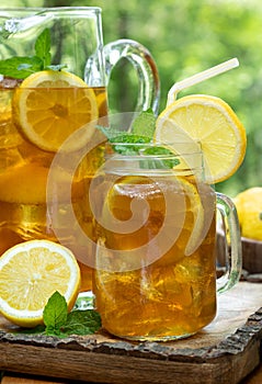 Ice tea in glass and pitcher with lemon and mint