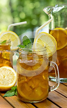 Ice tea in glass and pitcher with lemon and mint