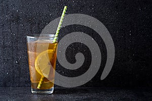 Ice tea with lemon. Black stone background