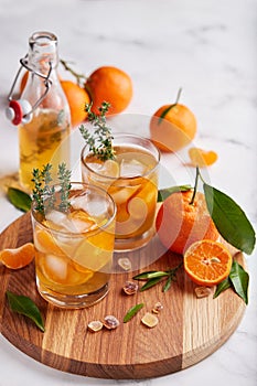 Ice tea with orange juice, ice cubes, and thymes. Refreshing summer beverage.