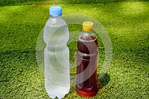 Mineral water and Ice tea in the plastic bottle on green grass background