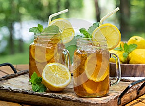 Ice tea in two glass jars with lemon and mint